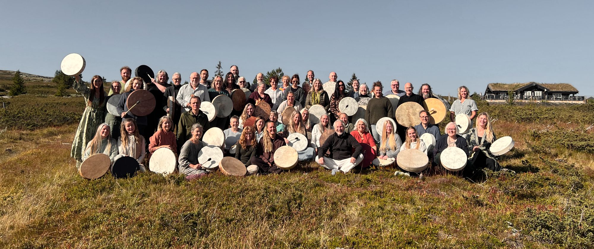 Seniorstudenter ved Yggdrasil sjamanskole samlet utendørs på fjellet, de fleste med tromme.